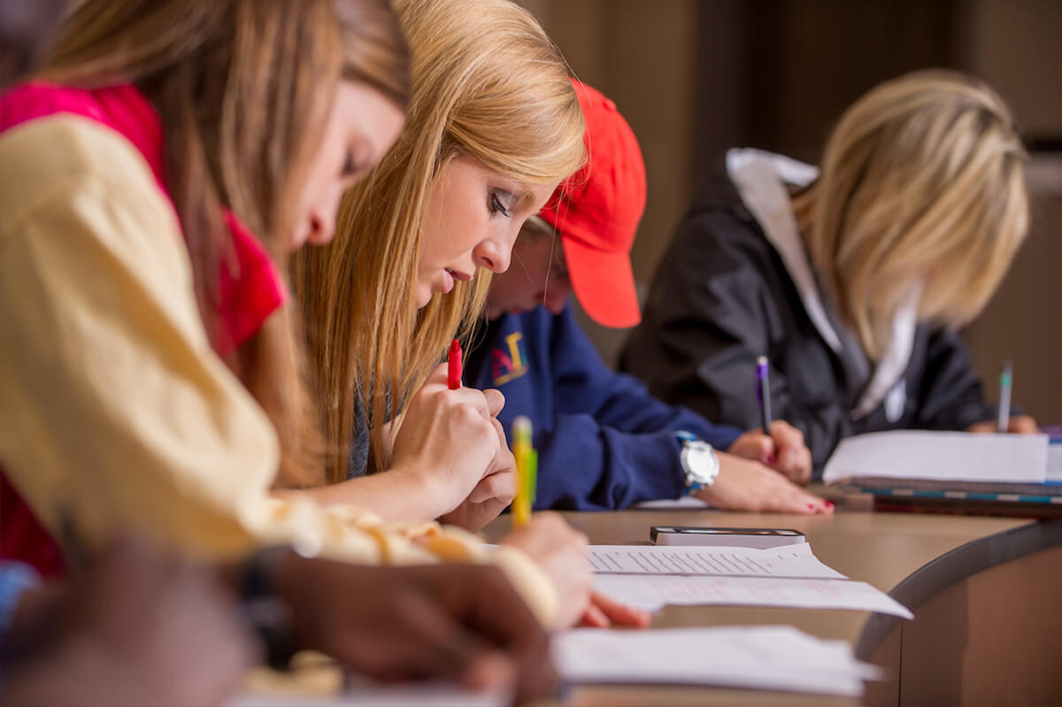 Arkansas State University students writing on paper.